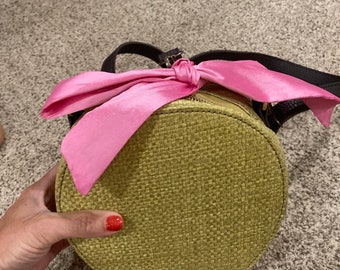 Green circular zipped bag with pink bow and additional ribbon to change out