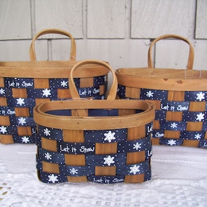 May include: Three wooden baskets with blue and white ribbon, decorated with white snowflakes and the text "Let it Snow".