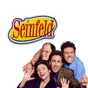 Può includere: Toppa ricamata con la scritta "Seinfeld" in rosso su sfondo giallo, bordata di blu e bianco. Sotto la toppa ci sono quattro persone sorridenti. L'immagine è su sfondo bianco.
