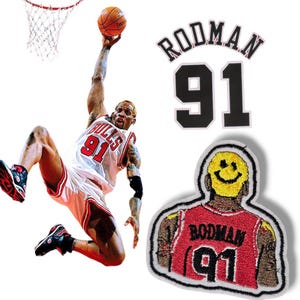 Puede incluir: Un parche blanco con el texto "RODMAN 91" en negro. Un segundo parche blanco con una camiseta de baloncesto roja y blanca con el texto "RODMAN 91" en negro. Un tercer parche blanco con una cara sonriente.