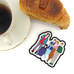 May include: Embroidered patch featuring a group of six cartoon figures in various poses. The figures are all wearing different coloured clothing, including red, blue, green, and yellow. The patch is white with a black outline.