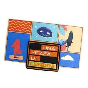May include: A colorful art print with a collage of images, including a red hand, blue lips, and a microphone. A black and orange patch with the text "UNA PEZZA DI LUNDINI" is in the foreground. The background is white.