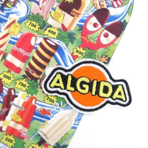 Può includere: Un primo piano di una toppa ricamata arancione e gialla con la parola "ALGIDA" in un cerchio bianco. La toppa è su uno sfondo di un'illustrazione colorata di gelati.
