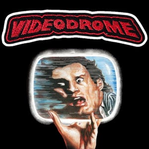 Könnte beinhalten: Ein schwarzer Aufnäher mit dem Wort "VIDEODROME" in roten, gestickten Buchstaben. Darunter ist ein verzerrtes menschliches Gesicht in einem Fernsehbildschirm zu sehen, der von einer Hand gehalten wird, vor schwarzem Hintergrund.