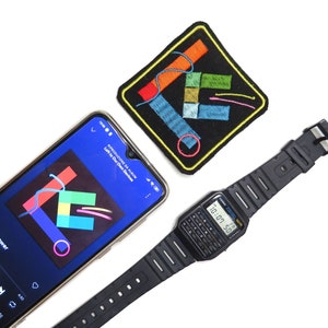 Puede incluir: Un reloj digital negro con una esfera de calculadora, un smartphone que muestra la carátula de un álbum y un parche bordado negro con formas geométricas coloridas. El reloj muestra la hora 10:07:50.