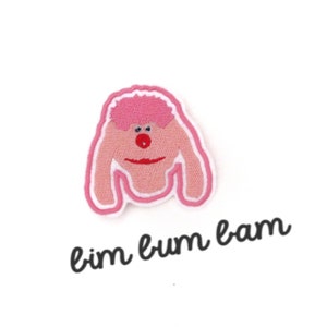 Op de afbeelding: Roze geborduurde patch van een cartoonfiguur met een roze pruik, rode neus en rode lippen. De tekst "bim bum bam" staat onder het figuur.