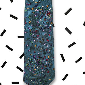 May include: A blue silk tie with a confetti pattern in various colours, including red, green, purple, and yellow.