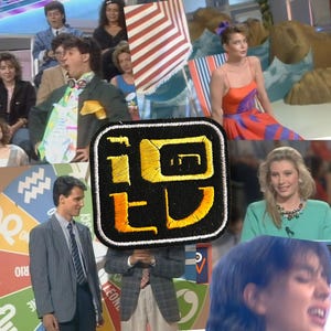 Peut inclure: Un plateau de télévision vintage avec un patch de logo au premier plan. Le patch est noir avec du texte brodé en jaune. Des personnes sont assises en arrière-plan, certaines portant des costumes et des robes. Des parasols de plage et une toile de fond colorée sont également visibles.