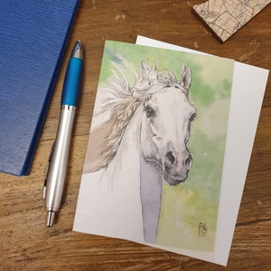 May include: A watercolour painting of a white horse with a green and yellow background. The horse's mane and tail are flowing in the wind.