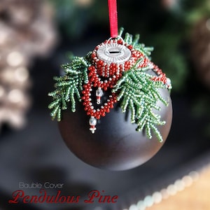 Op de afbeelding: Een zwarte kerstbal met een ontwerp van een groene dennentak met kralen en rode kralenaccenten. De bal heeft een zilveren dop en een rood lint.