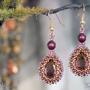 May include: A pair of gold earrings with a teardrop-shaped design. The earrings are made with small beads in shades of gold, pink, and purple. The earrings feature a larger, faceted, purple gemstone in the centre of each teardrop.