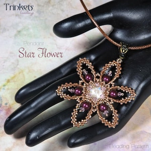 Op de afbeelding: Een ketting met een bloemvormige hanger. De hanger is gemaakt van goudkleurige kralen, donkerpaarse kralen en een centrale heldere kristal. Het bloemmotief is op een bruin leren koord. De tekst "Star Flower" is zichtbaar.