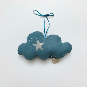 May include: A blue cloud-shaped stuffed toy with a silver glitter star and small white stars. The toy has a wooden ring attached to it and a teal ribbon.