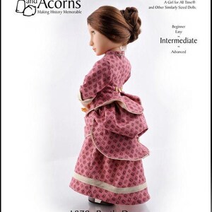 May include: A PDF sewing pattern for a 16-inch doll dress with a bustle. The dress is pink with a white floral print and has a white trim. The pattern is for a doll called "A Girl for All Time" and other similarly sized dolls. The pattern is labeled "1870s Bustle Dress" and is rated as "Intermediate" difficulty.