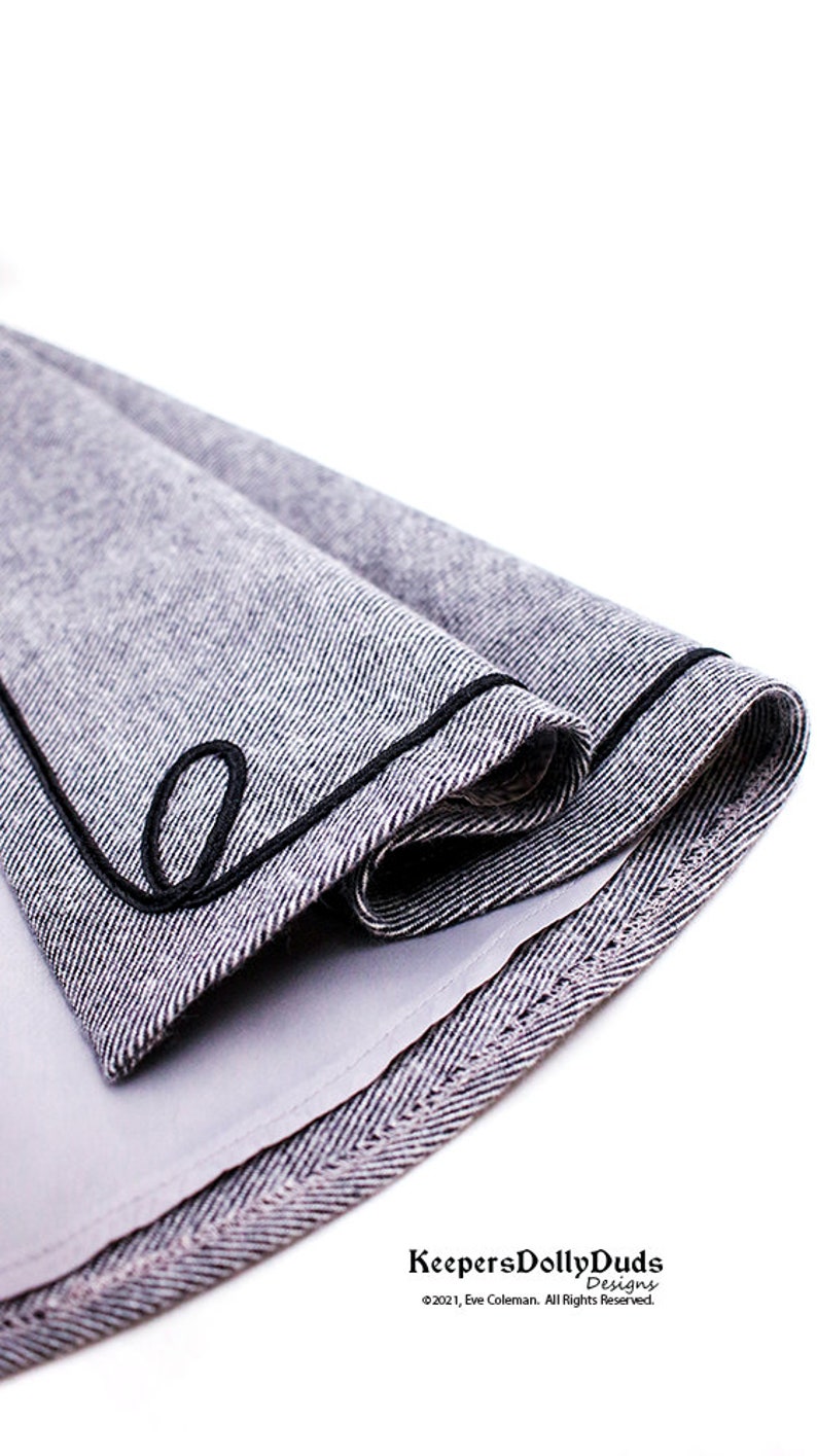 May include: A close-up of a gray and white fabric with a black trim. The fabric is folded in half and the trim is visible on the edge. The fabric is textured and has a herringbone pattern. The text "KeepersDollyDuds Designs &copy;2021, Eve Coleman. All Rights Reserved." is visible at the bottom of the image.