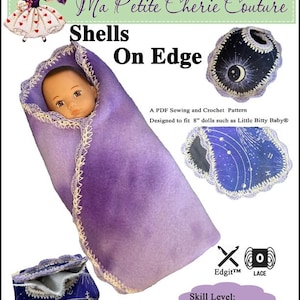 May include: A PDF sewing and crochet pattern for 8" dolls, featuring a doll swaddled in a purple blanket with a cream-colored trim. The design includes a doll carrier with a celestial pattern and the text "Shells On Edge". Skill level: Intermediate.