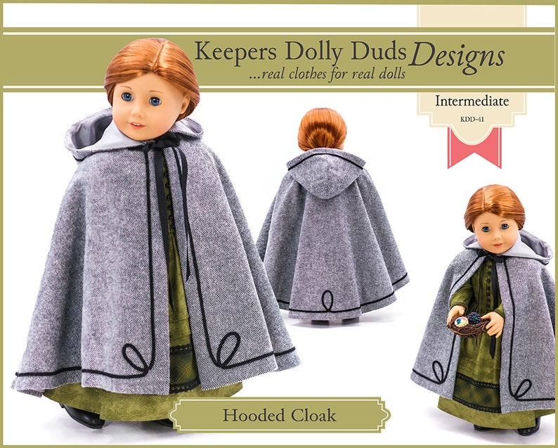 May include: A gray hooded cloak with black trim for a doll. The cloak has a hood and is made of a soft, fuzzy fabric. The doll is wearing a green dress underneath the cloak. The pattern is titled "Hooded Cloak" and is labeled "Intermediate" and "KDD-41".