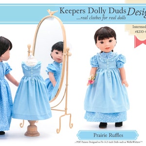May include: A blue and white patterned dress with a ruffled collar and sleeves. The dress is designed for 14.5-inch dolls. The pattern is called "Prairie Ruffles" and is labeled as "Intermediate #KDD-03".