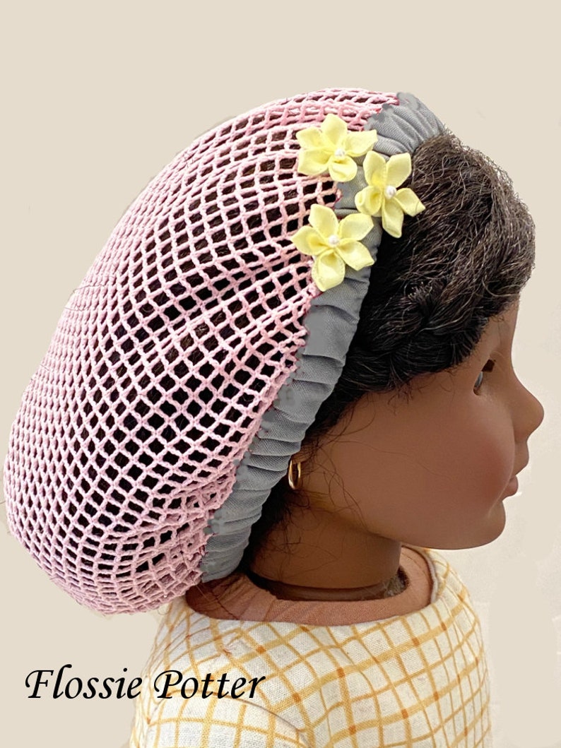 May include: A pink and gray hair net with yellow flower embellishments. The hair net is made of a mesh material and has a gray trim. The flowers are made of fabric and have a pearl center.