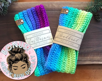 Puede incluir: Dos diademas de crochet hechas a mano, una en un arcoíris de colores y etiquetada "Handmade EarWarmer One of a Kind" y la otra en tonos azules y verdes etiquetada "Handmade Headband One of a Kind".