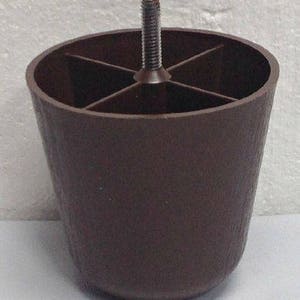 May include: A brown plastic furniture leg with a threaded metal screw. The leg has a textured surface and a circular base.