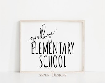Puede incluir: Una impresión enmarcada con las palabras "goodbye ELEMENTARY SCHOOL" en escritura negra y letras de bloque. La impresión tiene un fondo blanco y un marco de madera de color claro. Las palabras "Aspen Designs" están en la parte inferior.