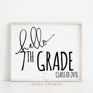 Könnte beinhalten: Ein weißer gerahmter Schild mit schwarzem Text, der "Hello 7th Grade Class of 2031" lautet. Der Text ist in einer handschriftlichen Schriftart.