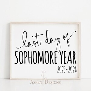 Könnte beinhalten: Ein gerahmtes Schild mit dem Text "last day of SOPHOMORE YEAR 2025-2026" in schwarzer Schrift und Blockbuchstaben. Das Schild hat einen weißen Hintergrund und einen hellen Holzrahmen. Die Worte "Aspen Designs" stehen unten.