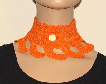 Puede incluir: Collar gargantilla de crochet naranja con un acento de flor de crochet blanco.