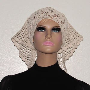 May include: A cream-colored, crocheted head covering with a square shape and a scalloped edge. The open weave design allows for breathability. The head covering is worn by a mannequin with a black top.