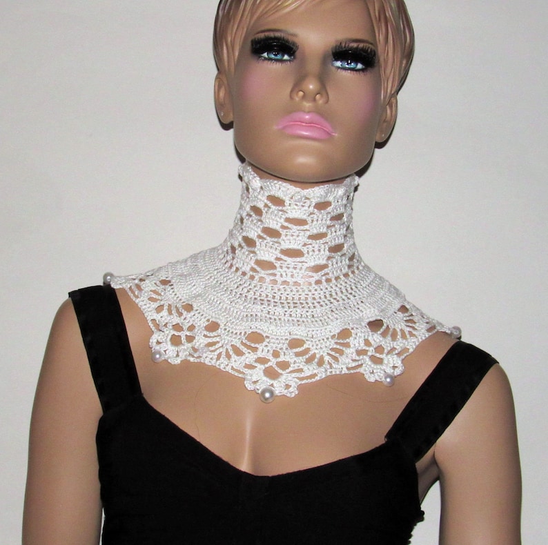 Puede incluir: Collar blanco de ganchillo con detalles de perlas. El collar es un dise&ntilde;o amplio y abierto con un borde festoneado.