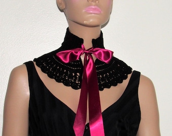 Puede incluir: Un collar de ganchillo negro con un gran lazo de satén rosa. El collar lo lleva un maniquí con el pelo corto y rubio.