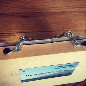 May include: A wooden box with a metal latch and a business card that reads "Traveling Soul Studio.com".