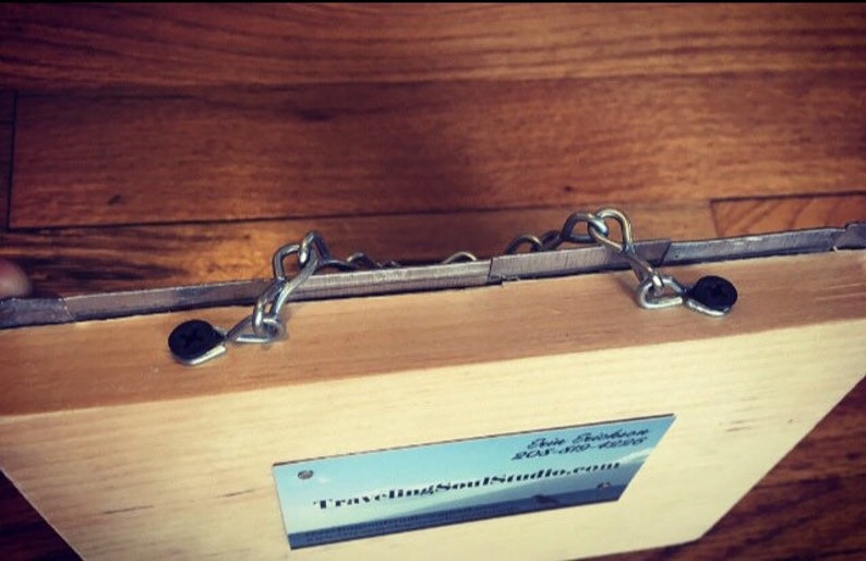 May include: A wooden box with two metal chains attached to the top. The box has a business card attached to the bottom with the text "TravelingSoulStudio.com".