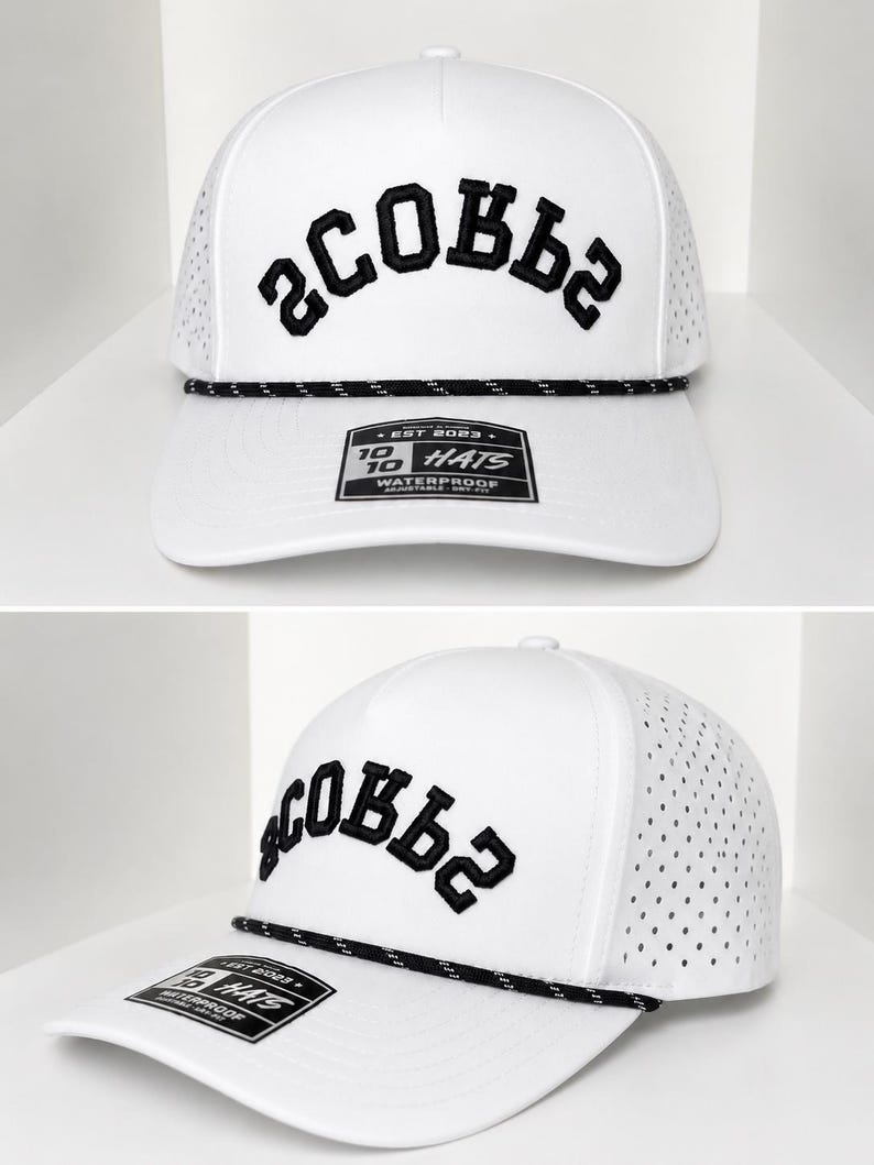 K&ouml;nnte beinhalten: Wei&szlig;e Baseballkappe mit schwarzem, gesticktem Text "SCOBBS". Die Kappe hat ein perforiertes Mesh-Seitenteil, ein schwarzes Seildetail und einen gebogenen Schirm. Ein Etikett mit Text ist am Schirm befestigt.