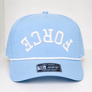 K&ouml;nnte beinhalten: Hellblaue Baseballkappe mit dem Wort "FORCE" in Wei&szlig;, das sich &uuml;ber die Vorderseite w&ouml;lbt. Die Kappe hat ein wei&szlig;es Seildetail und ein kleines rechteckiges Etikett. Die Kappe ist wasserdicht.