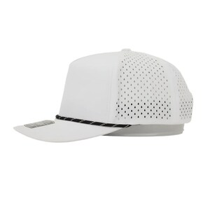 K&ouml;nnte beinhalten: Wei&szlig;e Baseballkappe mit flachem Schirm und schwarz-wei&szlig;em Seildetail. Die R&uuml;ckseite der Kappe hat ein perforiertes Design f&uuml;r Atmungsaktivit&auml;t. Die Kappe hat eine einfarbige wei&szlig;e Farbe.