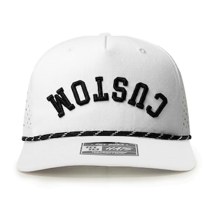 K&ouml;nnte beinhalten: Wei&szlig;e Baseballkappe mit dem Wort "CUSTOM" in Schwarz auf der Vorderseite gestickt. Sie hat eine schwarz-wei&szlig;e Seildetail am Rand und ein kleines Etikett. Die Kappe hat kleine Bel&uuml;ftungsl&ouml;cher.