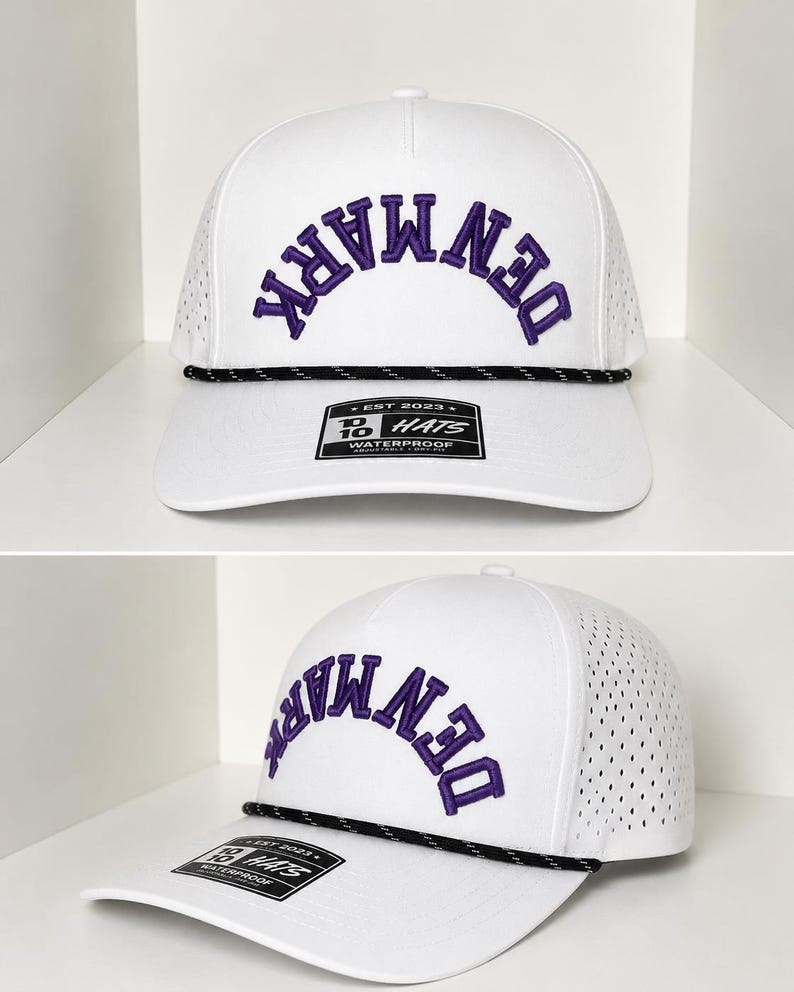 K&ouml;nnte beinhalten: Wei&szlig;e Baseballkappe mit dem Wort "DENMARK" in Lila auf der Vorderseite gestickt. Die Kappe hat ein schwarz-wei&szlig;es Seildetail und einen gebogenen Schirm. Die Kappe hat ein perforiertes Seitenteil und ein Etikett mit der Aufschrift "WATERPROOF".