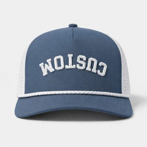 K&ouml;nnte beinhalten: Blau-wei&szlig;e Trucker-Cap mit dem Wort "CUSTOM" in wei&szlig;en Blockbuchstaben auf der Vorderseite. Die Kappe hat einen gebogenen Schirm, eine wei&szlig;e Mesh-R&uuml;ckseite und ein wei&szlig;es Seildetail &uuml;ber dem Schirm.