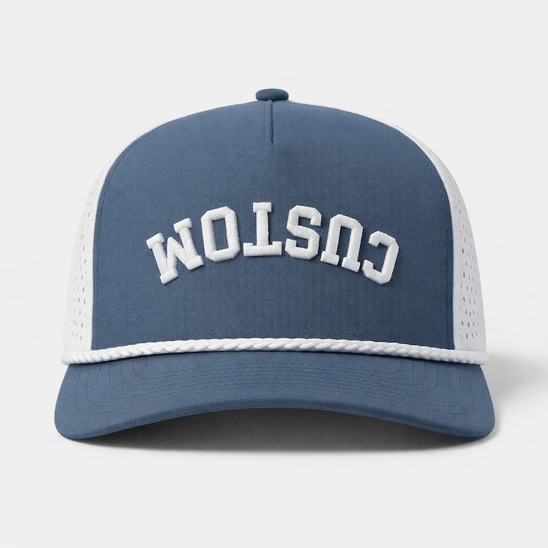 K&ouml;nnte beinhalten: Blau-wei&szlig;e Trucker-Cap mit dem Wort "CUSTOM" in wei&szlig;en Blockbuchstaben auf der Vorderseite. Die Kappe hat einen gebogenen Schirm, eine wei&szlig;e Mesh-R&uuml;ckseite und ein wei&szlig;es Seildetail &uuml;ber dem Schirm.