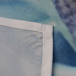 May include: Close-up of a white fabric edge with a blue and green tie-dye pattern in the background.