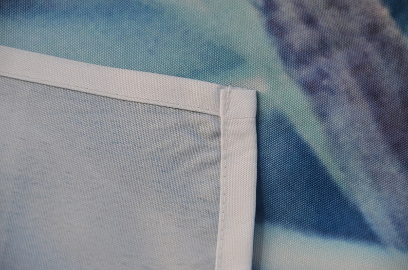 May include: Close-up of a white fabric edge with a blue and green tie-dye pattern in the background.