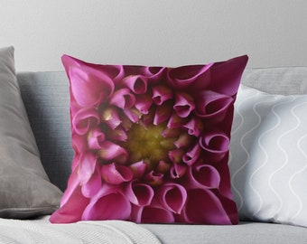 May include: A close-up of a vibrant pink dahlia flower. The petals are tightly packed together, creating a spiral pattern. The center of the flower is a golden yellow.