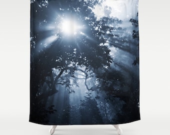 May include: A blue and white shower curtain featuring a photograph of a sun shining through the branches of trees in a forest.
