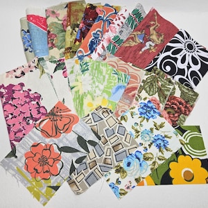 May include: A collection of assorted fabric squares with various floral, geometric, and abstract patterns. The fabrics feature a range of colors, including pink, blue, green, orange, and black, and are arranged on a white surface.