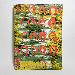 May include: A rectangular fabric item with a repeating pattern of orange shapes on a background of yellow, green, and black. The design has a textured appearance, with small black dots scattered throughout the pattern.