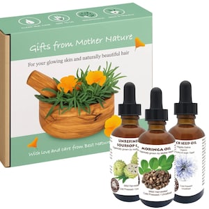 May include: A gift set labeled "Gifts from Mother Nature" includes three amber glass bottles of oil with droppers. The box features a wooden mortar and pestle filled with orange flowers. The text reads "For your glowing skin and naturally beautiful hair."