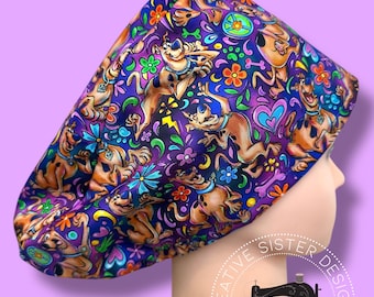 May include: A patterned scrub cap featuring a cartoon dog design in shades of brown, blue, purple, and orange. The cap is adorned with flowers, hearts, and lightning bolts. The cap is on a mannequin head.