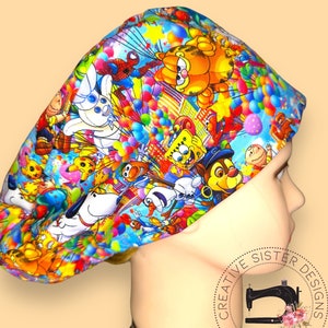 May include: A colorful surgical scrub hat with a cartoon character print featuring characters like Garfield, SpongeBob SquarePants, and Spiderman. The hat is blue with a white background and has a variety of colors throughout the print. The hat is on a mannequin head.